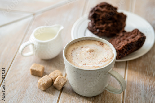 Cappuccino with cinnamon and chocolate chip muffin on wooden table background, coffee break