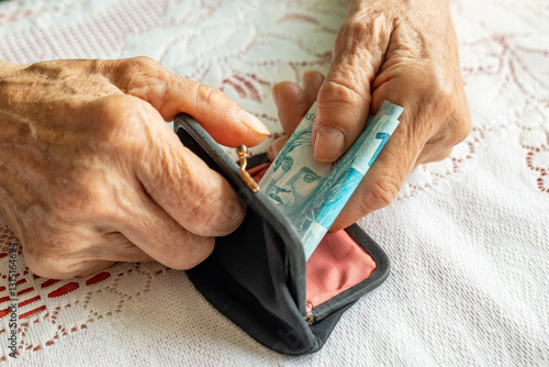 Obraz na płótnie Brazil money. Senior woman's hands holding a roll of banknotes. Financial concept. Brazilian finances w salonie