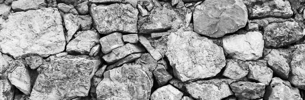 Fototapeta premium Stone wall texture. Natural stone background in gray tones with selective blur