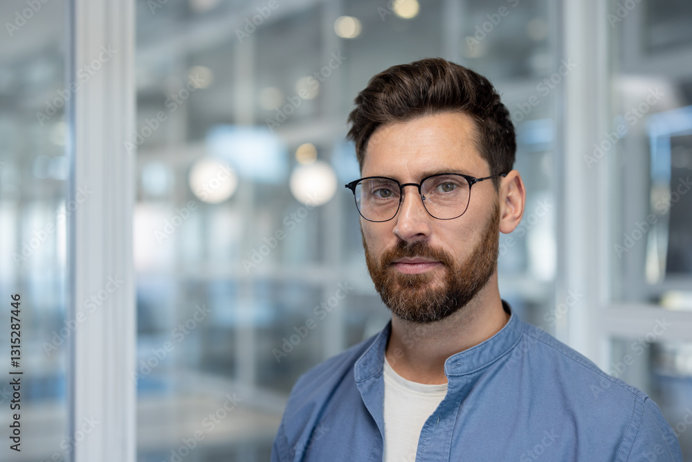 Portrait of a serious confident businessman, a man looks thoughtfully into the camera. A company developer employee close-up at his workplace inside the office. Portrait of a serious confident businessman, a man looks thoughtfully into the camera. A company developer employee close-up at his workplace inside the office.