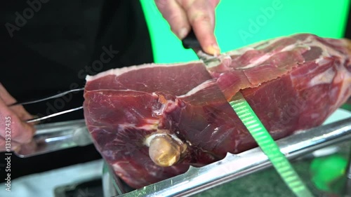 A chef skillfully slices a leg of cured ham with a sharp knife. Traditional gourmet food preparation, highlighting precision and craftsmanship in culinary art.