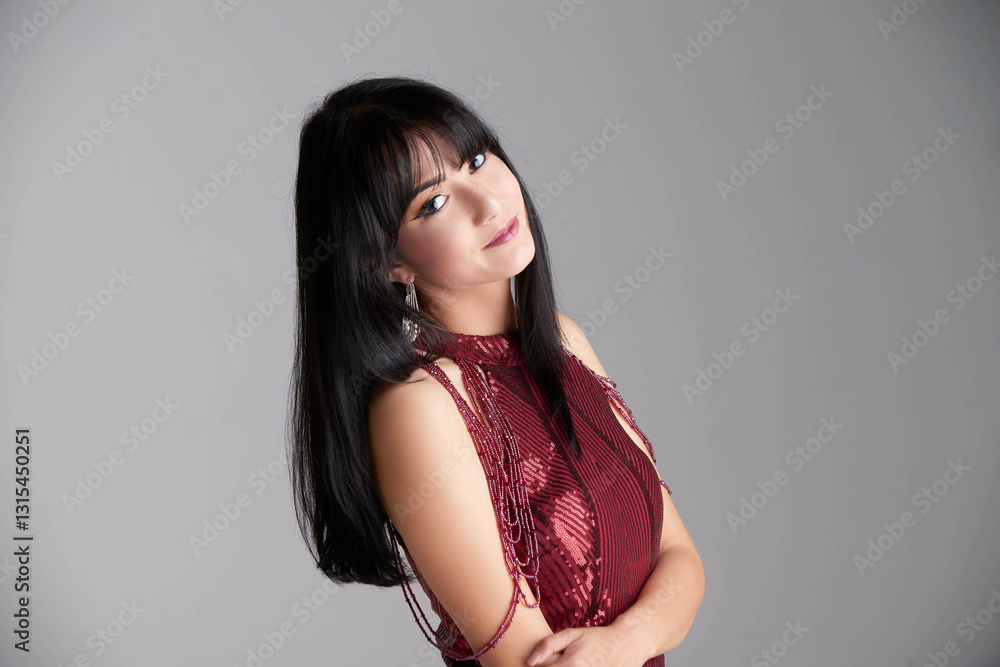 A photo of a beautiful brunette Caucasian Latina in a red elegant lounge dress, softly lit against a commercial white background.