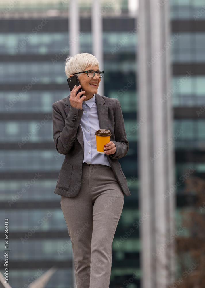 Fototapeta premium Businesswoman walking in urban environment and talking on phone