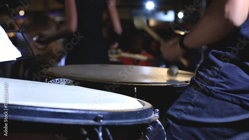orchestra musician playing timpani with drumsticks at night concert