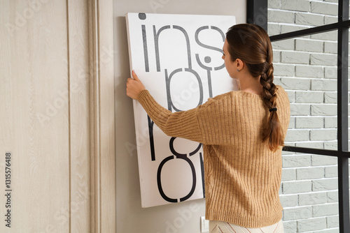 Young woman hanging poster ...