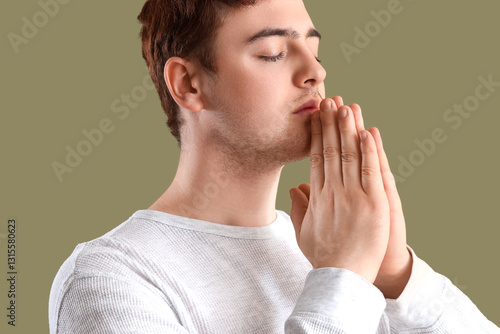 Young man praying on green ...