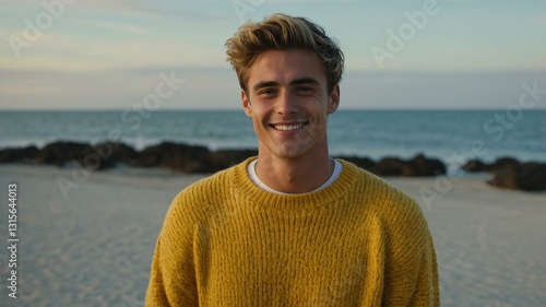 Good-looking young american guy in yellow themed sweater on a beach smiling
