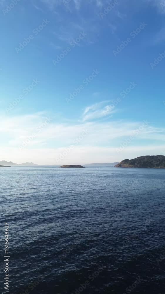 Camera moves forward and ascends from Baiona over the calm Atlantic Ocean, heading towards the Estelas Islands and Monteferro. The Cíes Islands and Vigo estuary are visible beyond on sunny afternoon. Camera moves forward and ascends from Baiona over the calm Atlantic Ocean, heading towards the Estelas Islands and Monteferro. The Cíes Islands and Vigo estuary are visible beyond on sunny afternoon.