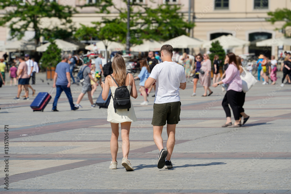Young couple strolling through a bustling square, capturing the essence of summer leisure amidst a lively crowd. Young couple strolling through a bustling square, capturing the essence of summer leisure amidst a lively crowd.