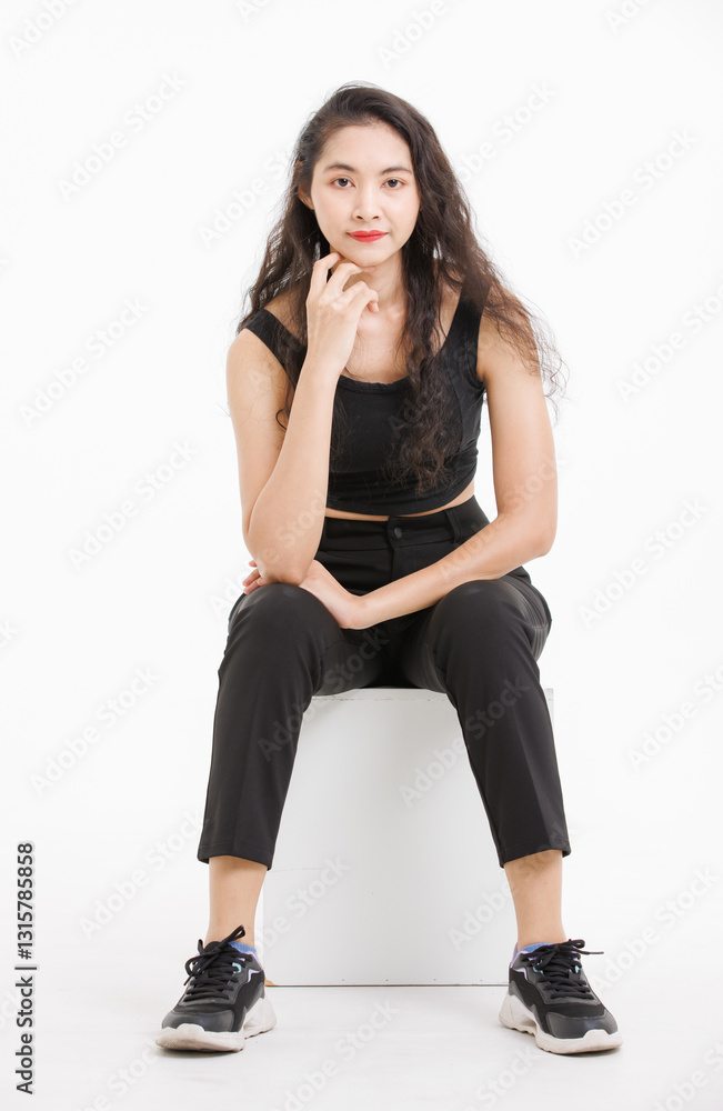 Portrait of asian beautiful woman with curly hair, wearing black tank top black long pants, model girl attractive confident, pose sitting on white box looking at camera on white background in studio. Portrait of asian beautiful woman with curly hair, wearing black tank top black long pants, model girl attractive confident, pose sitting on white box looking at camera on white background in studio.