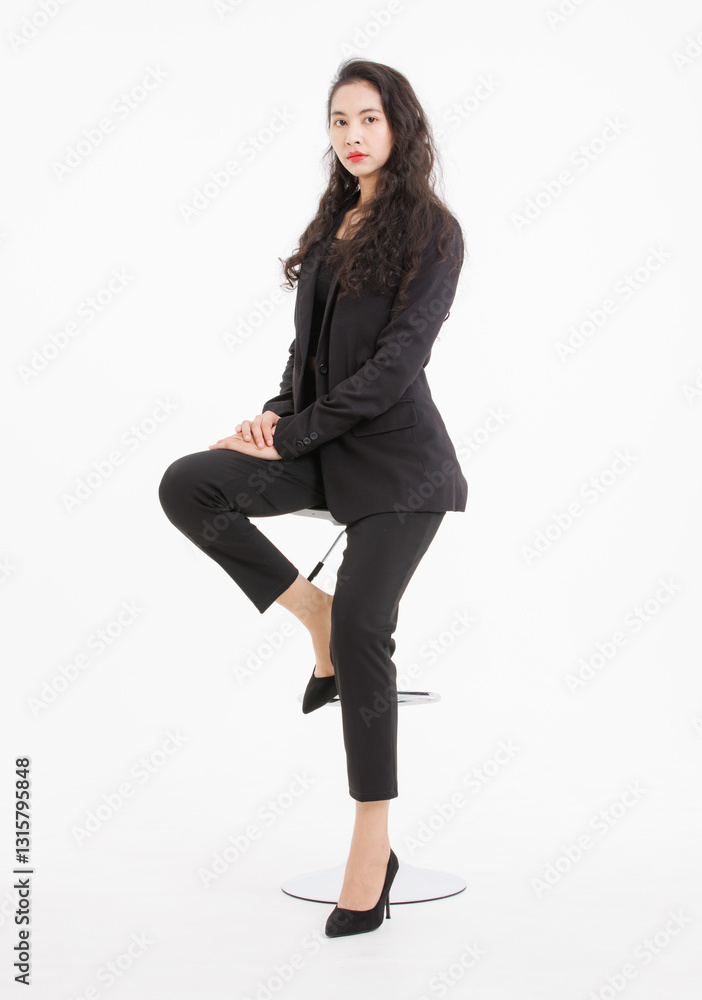 Portrait full body asian beautiful woman curly hair, wearing black suit, black long pants, model girl attractive confident, pose sitting on stool smiling look at camera on white background in studio. Portrait full body asian beautiful woman curly hair, wearing black suit, black long pants, model girl attractive confident, pose sitting on stool smiling look at camera on white background in studio.