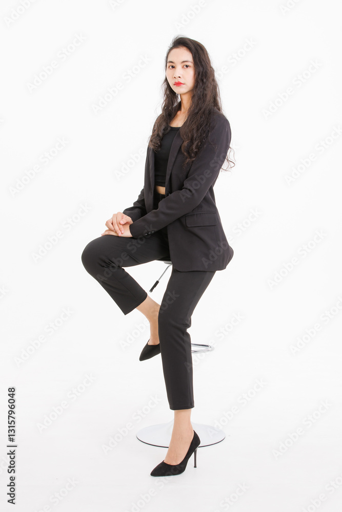Portrait full body asian beautiful woman curly hair, wearing black suit, black long pants, model girl attractive confident, pose sitting on stool smiling look at camera on white background in studio. Portrait full body asian beautiful woman curly hair, wearing black suit, black long pants, model girl attractive confident, pose sitting on stool smiling look at camera on white background in studio.