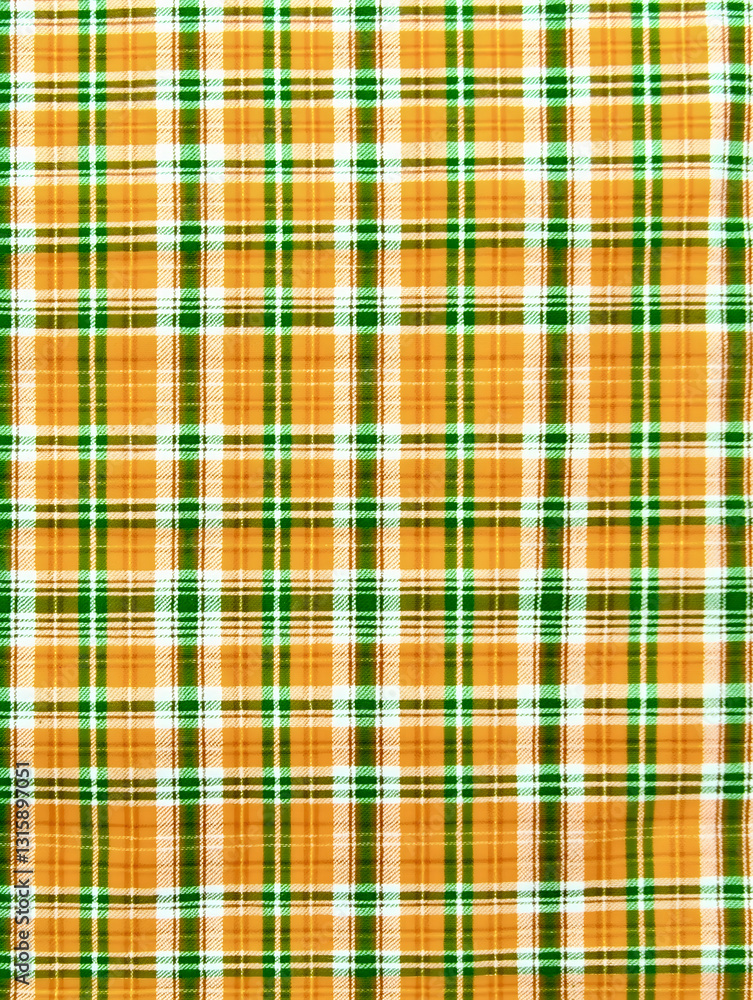 Obraz premium Colorful plaid fabric with a vibrant pattern showcasing green and orange hues ideal for various textile projects
