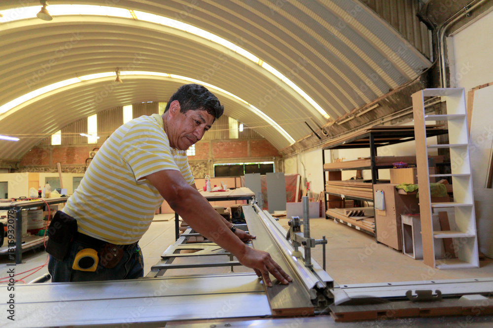 Fototapeta premium Carpenter cuts a board on the power saw