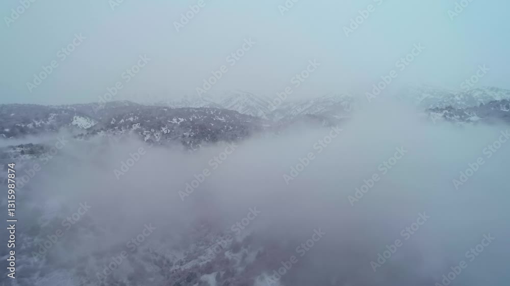 The drone flies through the clouds over the snow-covered mountains. Cloudy winter day The drone flies through the clouds over the snow-covered mountains. Cloudy winter day