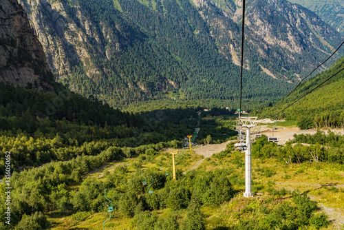 Cable car descending into lush valley in mountain range photo