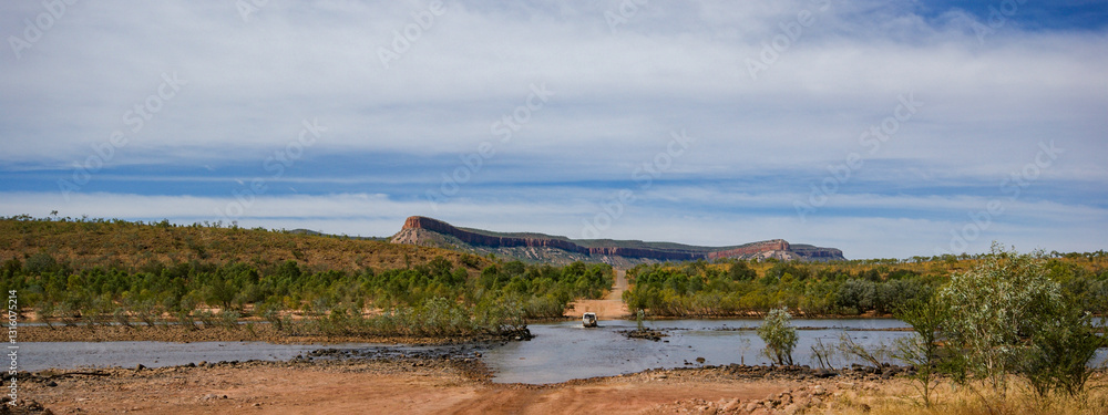 Fototapeta premium Vehicle crossing the Pentecost river on Gibb river road, Cockburn Range in background, Kimberleys, Western Australia