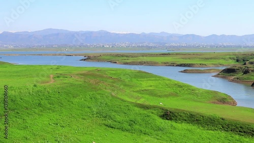 Vibrant green landscapes merging with a river and high mountain scenery