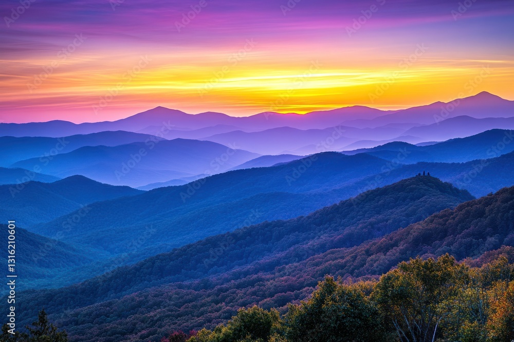 Fototapeta premium Vibrant sunset over layered blue mountains.