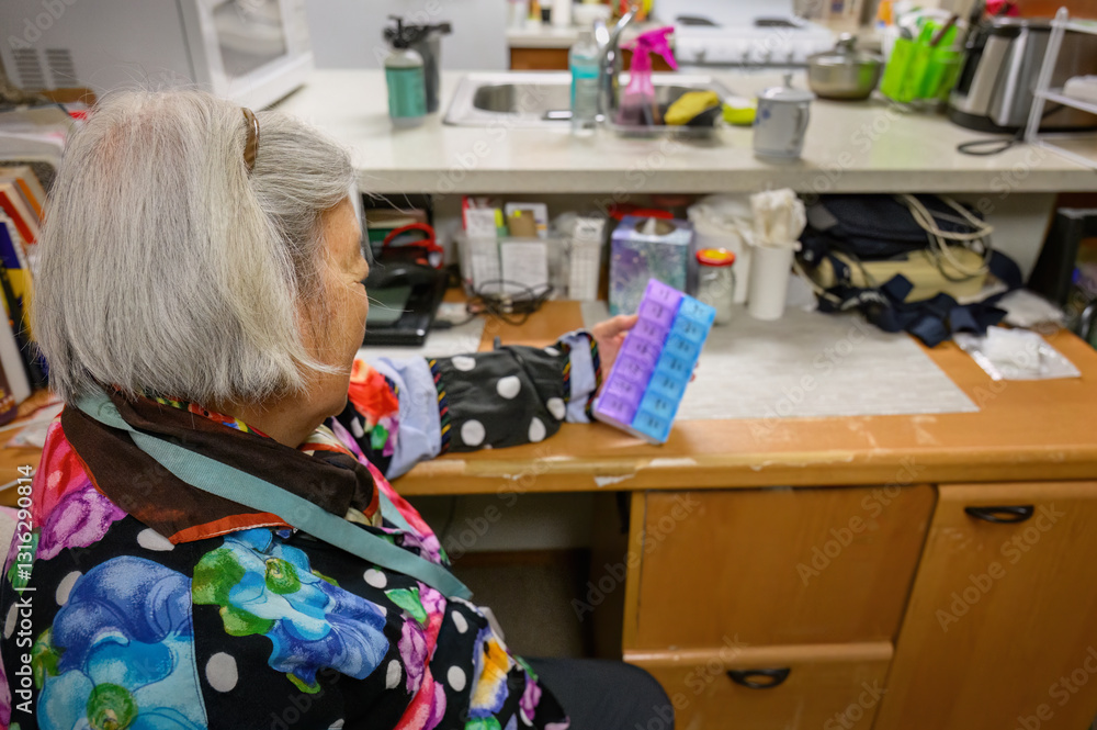 Elderly woman holding a pill box in her home.