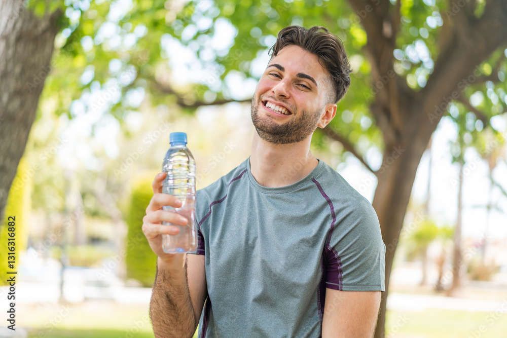 Young handsome sport man with a bottle of water at outdoors smiling a lot Young handsome sport man with a bottle of water at outdoors smiling a lot