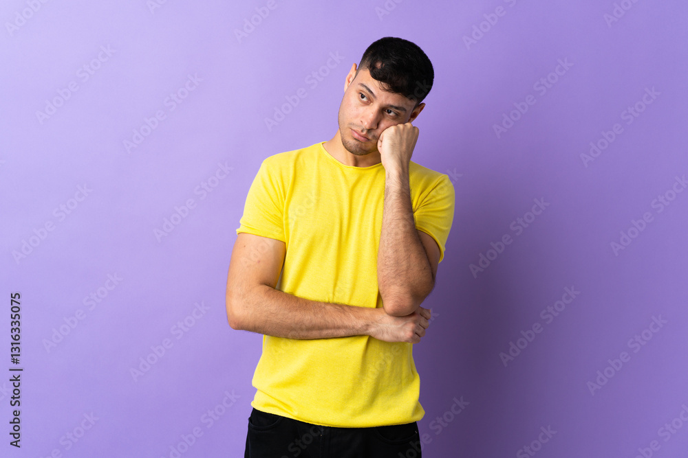 Young Colombian man isolated on purple background with tired and bored expression Young Colombian man isolated on purple background with tired and bored expression