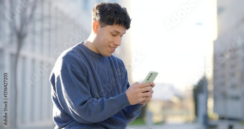 Young latin man using smartphone in urban setting