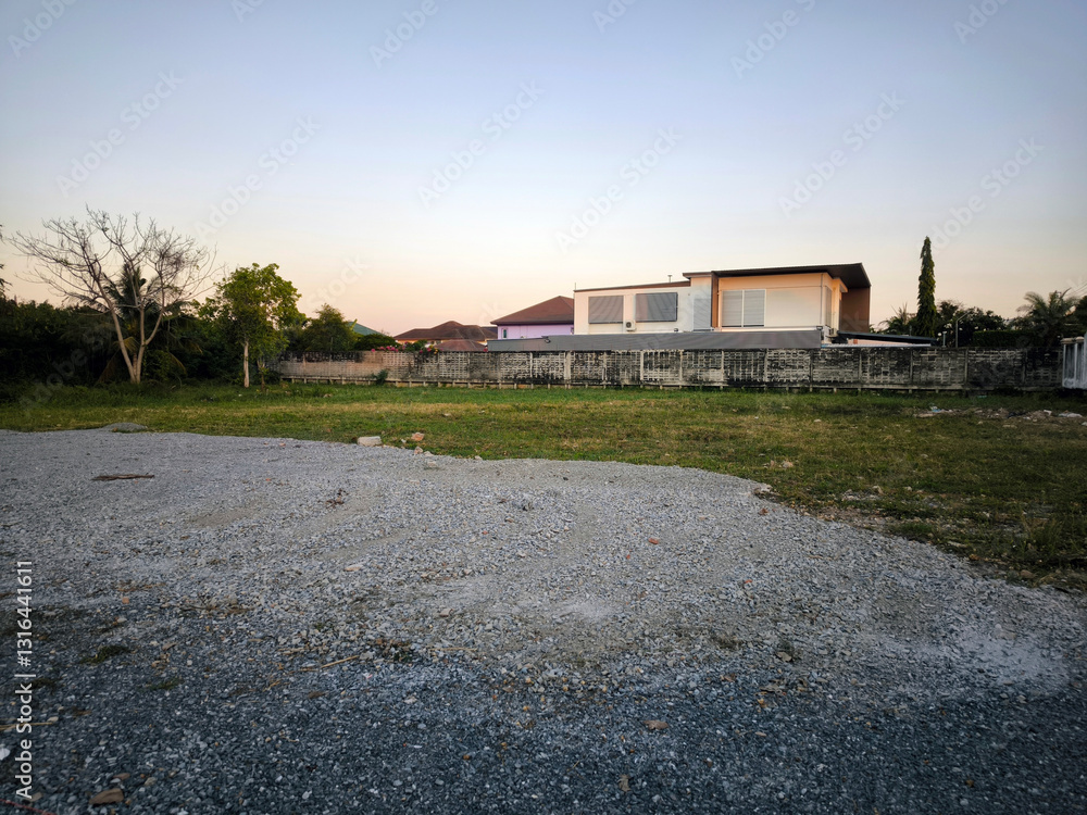 Obraz premium Empty Gravel Lot Near Residential Homes at Sunset