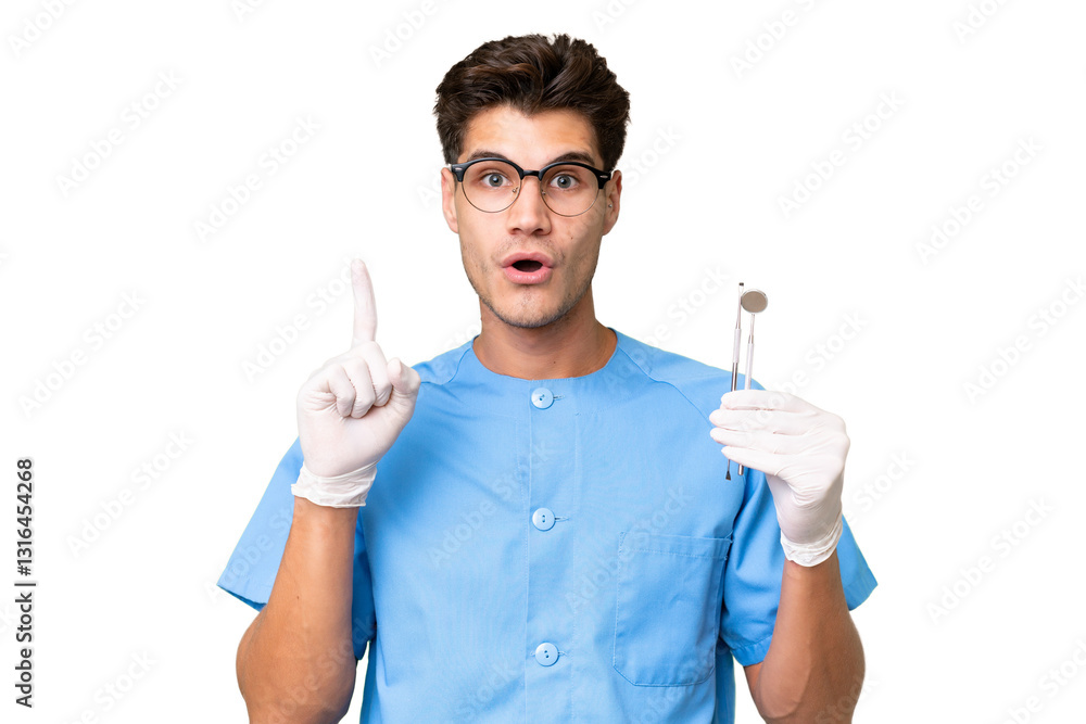 Young dentist man holding tools over isolated background thinking an idea pointing the finger up Young dentist man holding tools over isolated background thinking an idea pointing the finger up