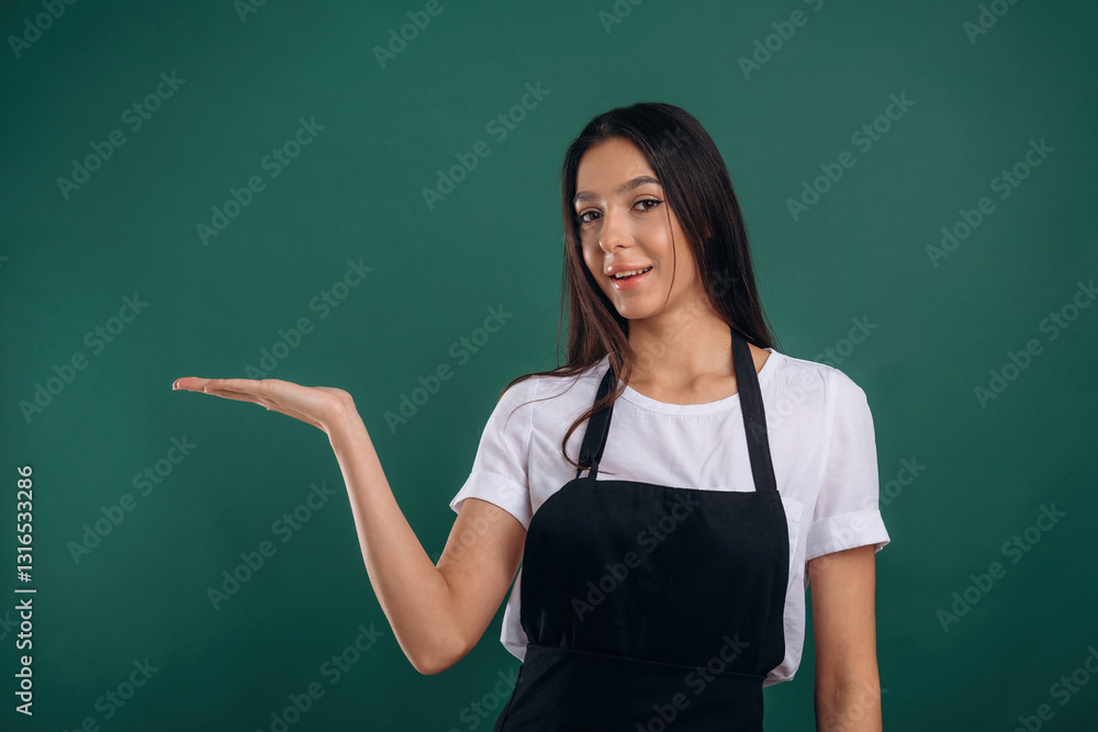 Copy space, showing invisible object. Young beautiful barista is against background Copy space, showing invisible object. Young beautiful barista is against background