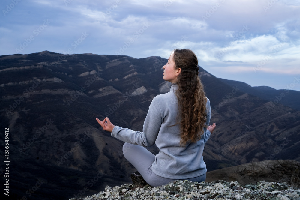 Naklejka premium Young traveler woman meditating in yoga asana Padmasana. Female yogis practice yoga and meditation in the mountains. A calm yogi doing yoga at the sunset. Spiritual practice outdoors. Nature, people.