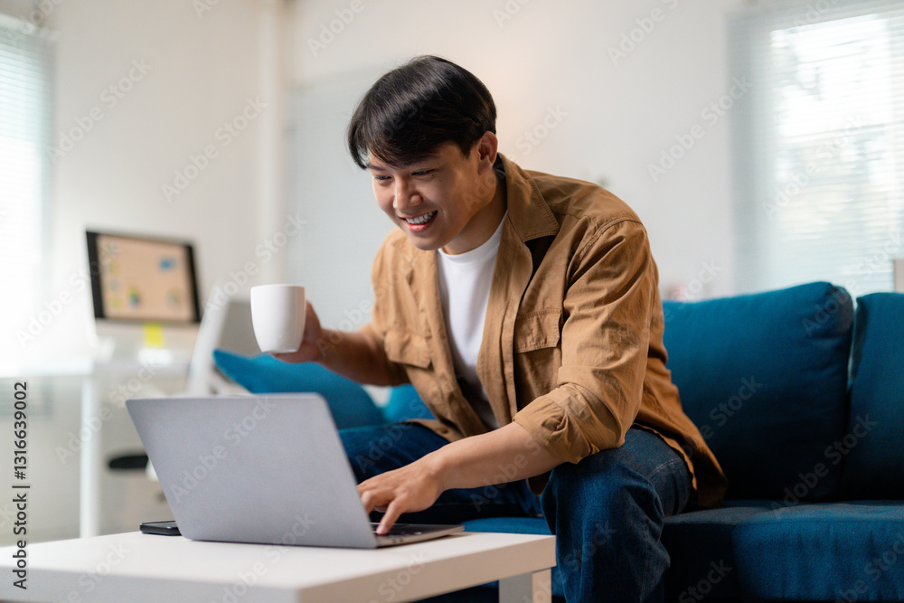 Happy young man using laptop and drinking coffee, working from home Happy young man using laptop and drinking coffee, working from home