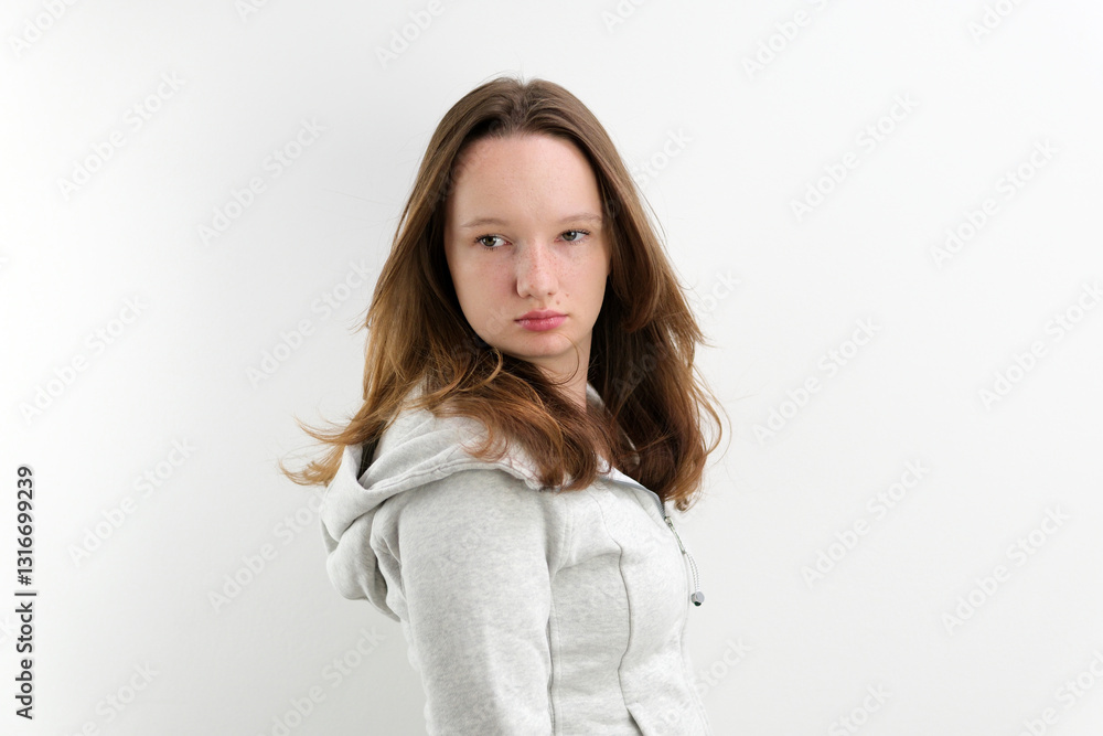 young teenage girl in sporty gray sweater different emotions facial expressions loose brown hair on white background Fashion model posing gracefully in minimalist studio, beauty, elegance and modern
