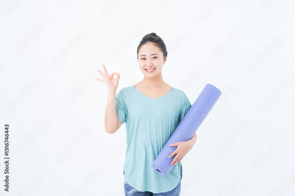 ヨガマットを持つ若い女性