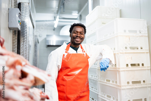 Fotografia Slaughterhouse worker standing in meat cold storage of butchery shop
