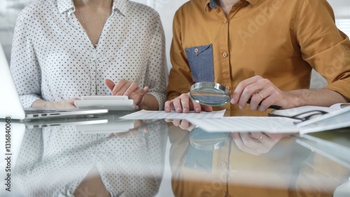 Foto Two accountants conducting a financial audit in their office, closely examining documents with a magnifying glass and calculator