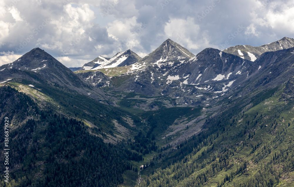 Fototapeta premium snow-capped mountain hills and dark rainy sky 