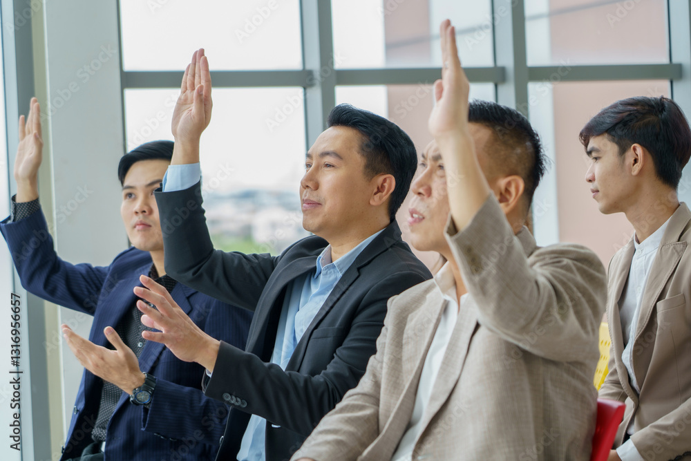 Obraz premium group of asian business people sitting in meeting at seminar or listener raising hand to ask question. audience hand up