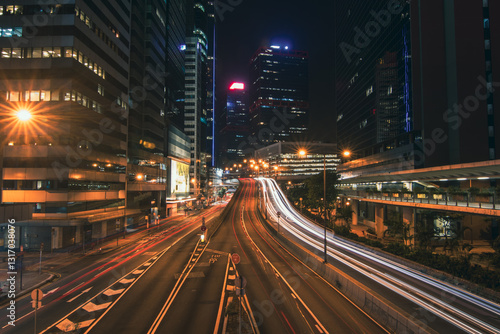 A mesmerizing long exposure photograph of Hong Kong's vibrant cityscape at night. Towering skyscrapers pierce the inky sky, their illuminated windows creating a dazzling tapestry of light. 