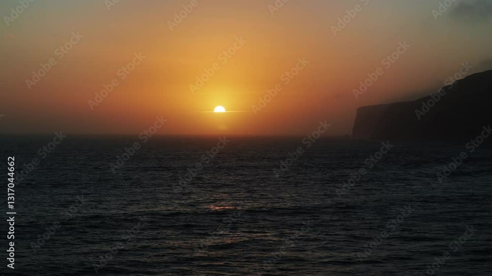 The sun is setting over the ocean, casting a warm glow on the water. The sky is a mix of orange and pink hues, creating a serene and peaceful atmosphere. The ocean is calm and still The sun is setting over the ocean, casting a warm glow on the water. The sky is a mix of orange and pink hues, creating a serene and peaceful atmosphere. The ocean is calm and still