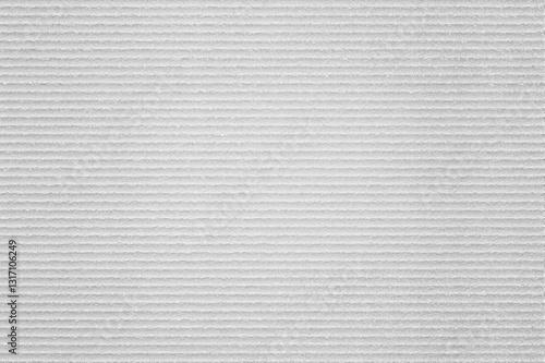 A textured white surface with horizontal linear patterns, resembling a ribbed fabric or material backdrop.
