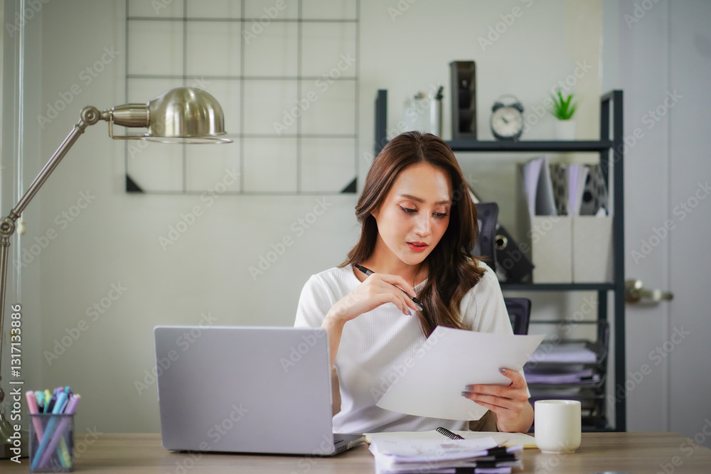 A woman is sitting at a desk with a laptop and a stack of papers A woman is sitting at a desk with a laptop and a stack of papers