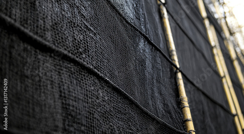 Detailed shot highlights black safety netting on a construction site, showcasing its texture and secure design during installation