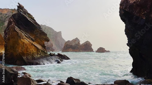 Beautiful rocky coast beside the Atlantic. The popular Portuguese Ursa Beach. Beautiful panoramic view of the rocky shore with incoming blue waves. Beautiful ocean against a background of rocks.