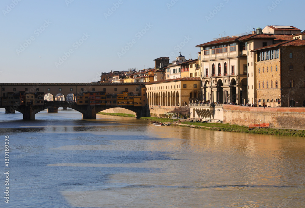 Fototapeta premium Ponte Vecchio and historic buildings in the historic center of Florence in Italy and the wide Arno river that divides the Italian city in two