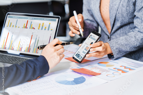 Wallpaper Mural Two female business professionals in suits sit at desk, engaged in strategic discussion. They analyze financial planning, risk management, corporate growth while reviewing reports and market trends. Torontodigital.ca