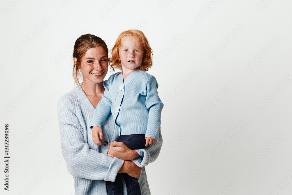 Mother and daughter in coordinated outfits standing together in studio for family fashion photoshoot Mother and daughter in coordinated outfits standing together in studio for family fashion photoshoot