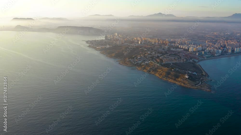 Aerial view of the sunset in Cabo Huertas, and the buildings next to San Juan Beach in the Mediterranean city of Alicante, Spain. Aerial view of the sunset in Cabo Huertas, and the buildings next to San Juan Beach in the Mediterranean city of Alicante, Spain.
