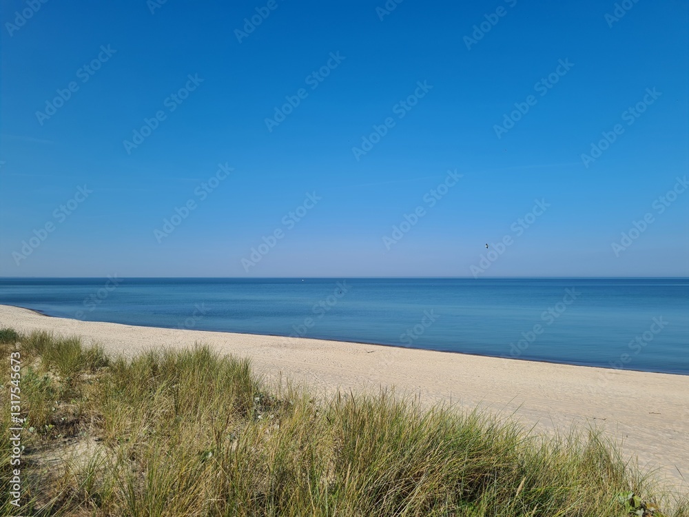 Spokojna piaszczysta plaża nad Morzem Bałtyckim, z błękitną wodą, czystym niebem i nadmorskimi wydmami porośniętymi trawami, letni krajobraz. Spokojna piaszczysta plaża nad Morzem Bałtyckim, z błękitną wodą, czystym niebem i nadmorskimi wydmami porośniętymi trawami, letni krajobraz.