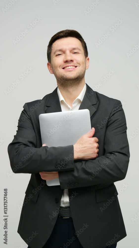 Confident businessman poses with a laptop, showcasing a friendly demeanor in a studio environment. Confident businessman poses with a laptop, showcasing a friendly demeanor in a studio environment.